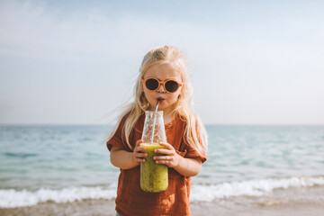 Vegan breakfast child drinking smoothie on beach healthy eating lifestyle plant based food organic fruit nutrition kid girl with reusable glass bottle and metal straw summer vacations - obrazy, fototapety, plakaty