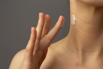 Closeup of a young woman applying prescription retinoid to her neck.