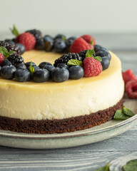 Close up cheesecake decorated with blueberry, raspberry, blackberry and leaves of mint