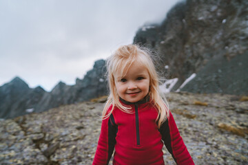 Naklejka na ściany i meble Child girl hiking in mountains travel vacations adventure outdoor healthy lifestyle happy smiling kid portrait