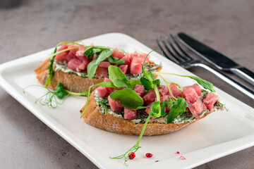two bruschettas with tuna, Sandwiches with tuna tartare on the white plate