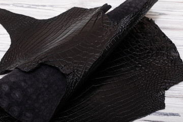 black dyed genuine natural alligator leather on the wooden table	