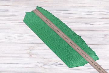  green blue dyed genuine natural alligator leather on the wooden table	