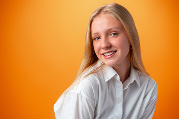 Portrait of smiling young teen girl against orange background