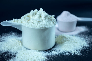 Whey protein powder scoop. Sports nutrition on black background