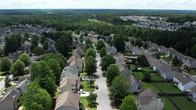 Pull away drone aerial view over an American lush green suburban neighborhood.