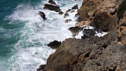 Crystal clear turquoise water, waves crashing on the rocky shore, and the ruins