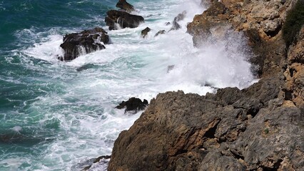 Crystal clear turquoise water, waves crashing on the rocky shore, and the ruins