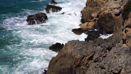 Crystal clear turquoise water, waves crashing on the rocky shore, and the ruins