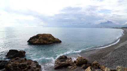 Crystal clear turquoise water, waves crashing on the rocky shore, and the ruins