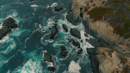 Crystal clear turquoise water, waves crashing on the rocky shore, and the ruins