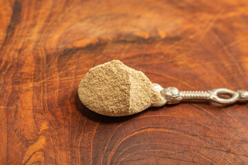 silver teaspoon full of grounded white pepper , on a wooden chopper