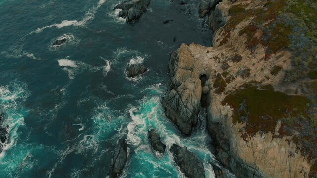 Crystal clear turquoise water, waves crashing on the rocky shore, and the ruins