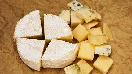 Different varieties of cheese. Soft french cheese of camembert and other types on craft paper