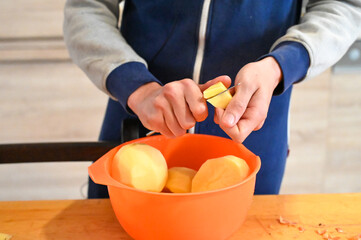 A man peels and cuts potatoes. Lunch preparation.