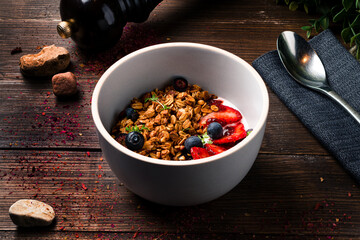 Healthy breakfast ingredients. Bowl of oat granola with fresh berries and honey. Top view
