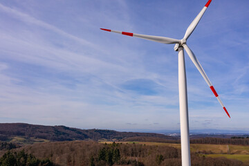 Luftaufnahme einer rot-weißen Windkraftanlage mit drei Rotorblättern auf einem Berg gegen den...