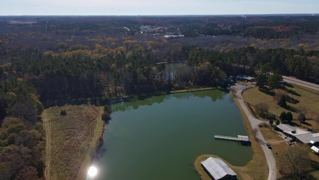 Aerial drone fly over green lake with sun burst on the left of the lake