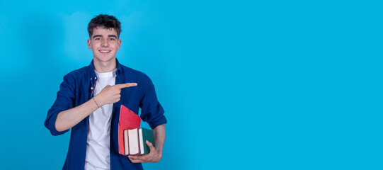student with books isolated on blue background pointing