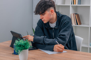 teen boy at home studying with computer or tablet