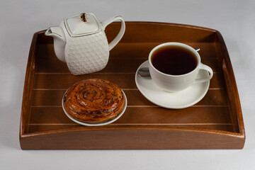 a cup of tea with a bun on a tray