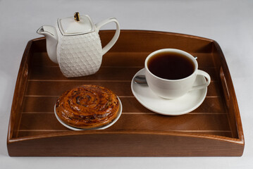 a cup of tea with a bun on a tray
