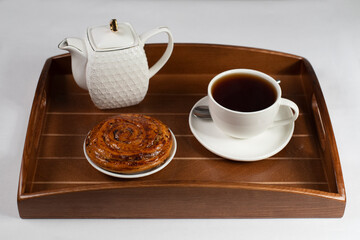 a cup of tea with a bun on a tray