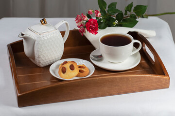 a cup of tea with cookies and a rose on a tray