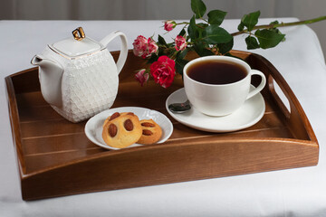 a cup of tea with cookies and a rose on a tray
