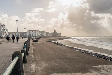 Gordijnen Backlit shot of the beach and boulevard near the Dutch town of Flushing on a cold winter's day with a stormy wind. It is quiet and only few people are outside. © Ruud Morijn