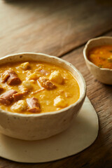 Mote pata is a traditional ecuadorian soup made from mote, pork, sausage and sambo seeds. It’s served on a white plate with a rustic, wooden and homey background. 