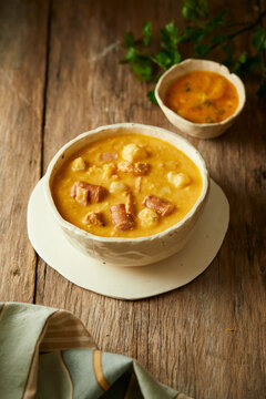 Mote pata is a traditional ecuadorian soup made from mote, pork, sausage and sambo seeds. It&rsquo;s served on a white plate with a rustic, wooden and homey background. 