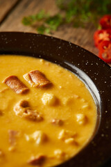 Mote pata is a traditional ecuadorian soup made from mote, pork, sausage and sambo seeds. It’s served on a white plate with a rustic, wooden and homey background. 