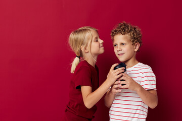 boy and girl are standing next to a disposable glass with a drink red background