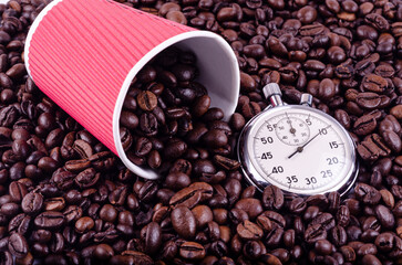 Red paper cup and stopwatch on a background of coffee beans