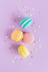 Tasty french macaroons on a violet pastel background.