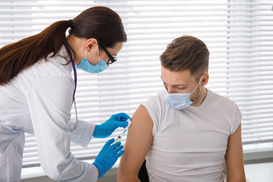 The Doctor Holds A Syringe Before Giving An Injection To A Patient In A Medical Mask. Covid-19 Or Coronavirus Vaccine. Vaccination Of The Population Concept.