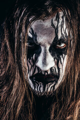 Portrait photo of black metal metalhead man with long brown hair and painted face on black...