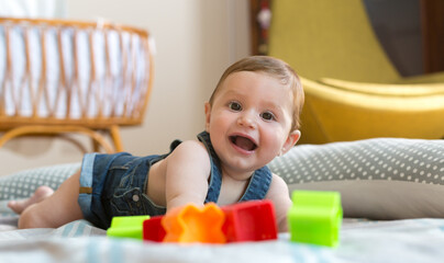 Happy and cheerful 8 months baby playing at home with colored bricks