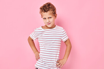 Funny happy kid in a striped t-shirt pink color background