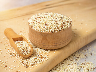 Raw mixed quinoa in bowl and scoop on light concrete background. Healthy and diet superfood