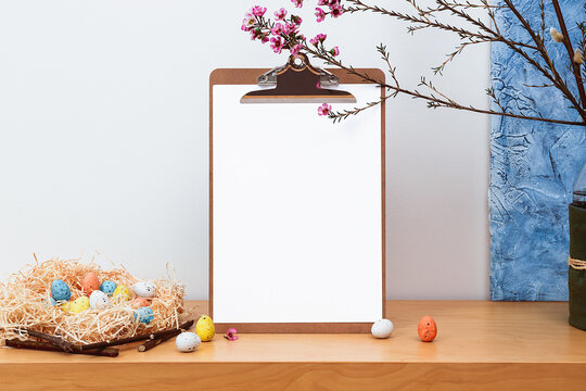 Spring still life. Blank picture frame mockup on wooden table background. Easter composition with blooming pussy willow and waxflowers in vase