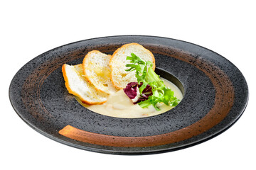 Delicious creamy soup served with leaves and toastes isolated on
