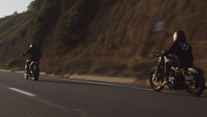 Motorcyclists riding beautiful bikes along a coastal highway. Back view of the bikers driving within cinematic mountainous landscape in California. High quality 4k footage