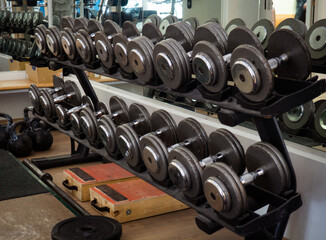 Naklejka na ściany i meble Rows of dumbbells in the gym. Rack with heavy dumbbells in a fitness club. Workout bodybuilding concept.