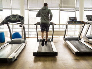 Fototapeta premium guy jogging on a treadmill in the gym. Fitness, workout and healthy lifestyle