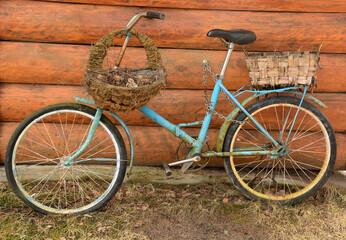 Fototapeta na wymiar An old rusty Soviet bicycle near a wooden background with two baskets - flower beds