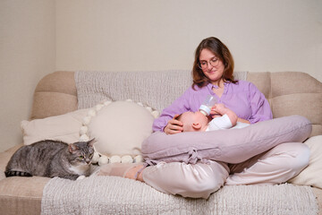 Woman mother feeds infant baby formula from a bottle