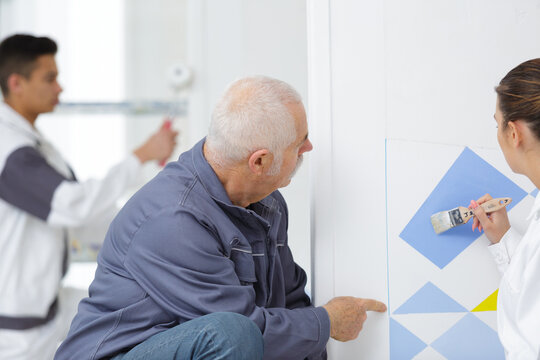 teacher guiding a painting apprentice