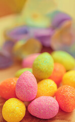 Easter sweet, pink, yellow, green eggs and blurred flowers. Background.